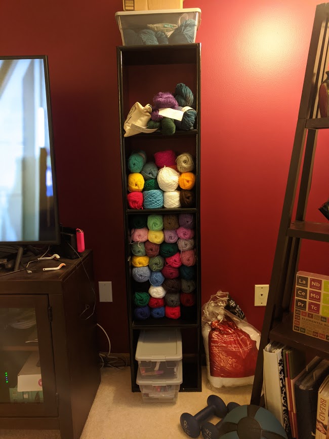 A black shelving unit filled with colorful skeins and balls of yarn.