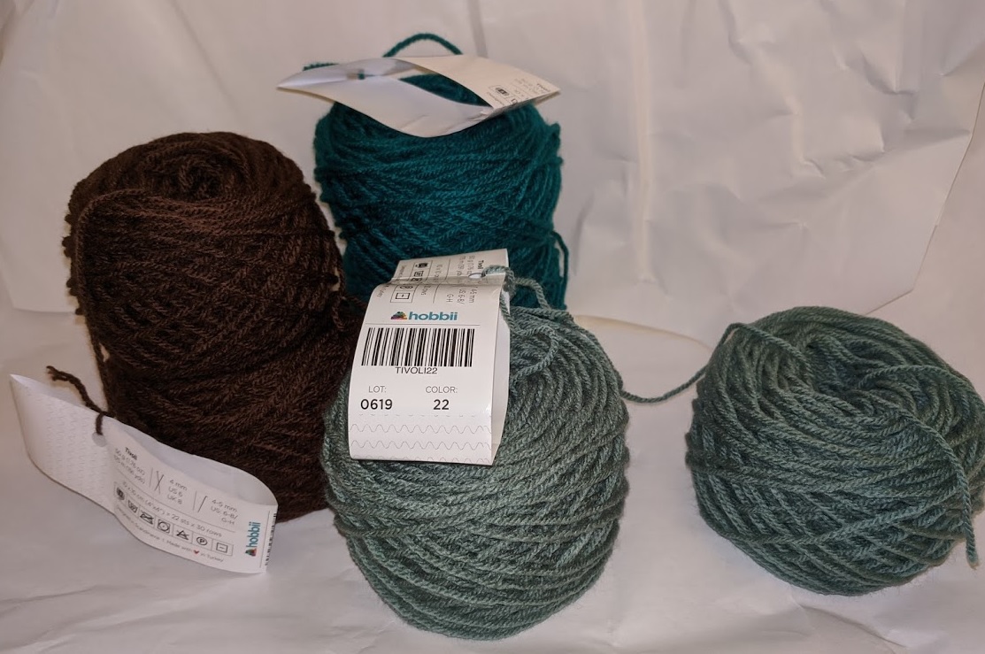 Cakes of yarn stacked in brown and green.