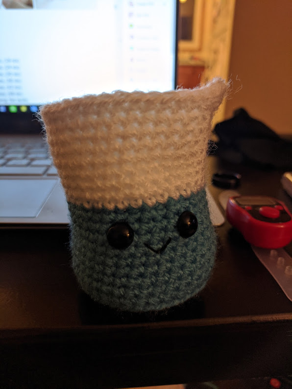 Small crocheted beaker made with blue and white yarn.