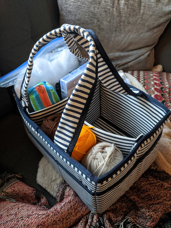 A divided bag with 3 compartments, one holding yarn and one holding tools.