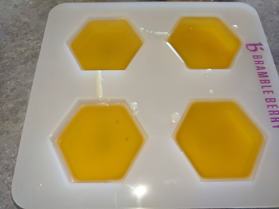 Bright yellow liquid in 4 hexagons in a silicone mold.