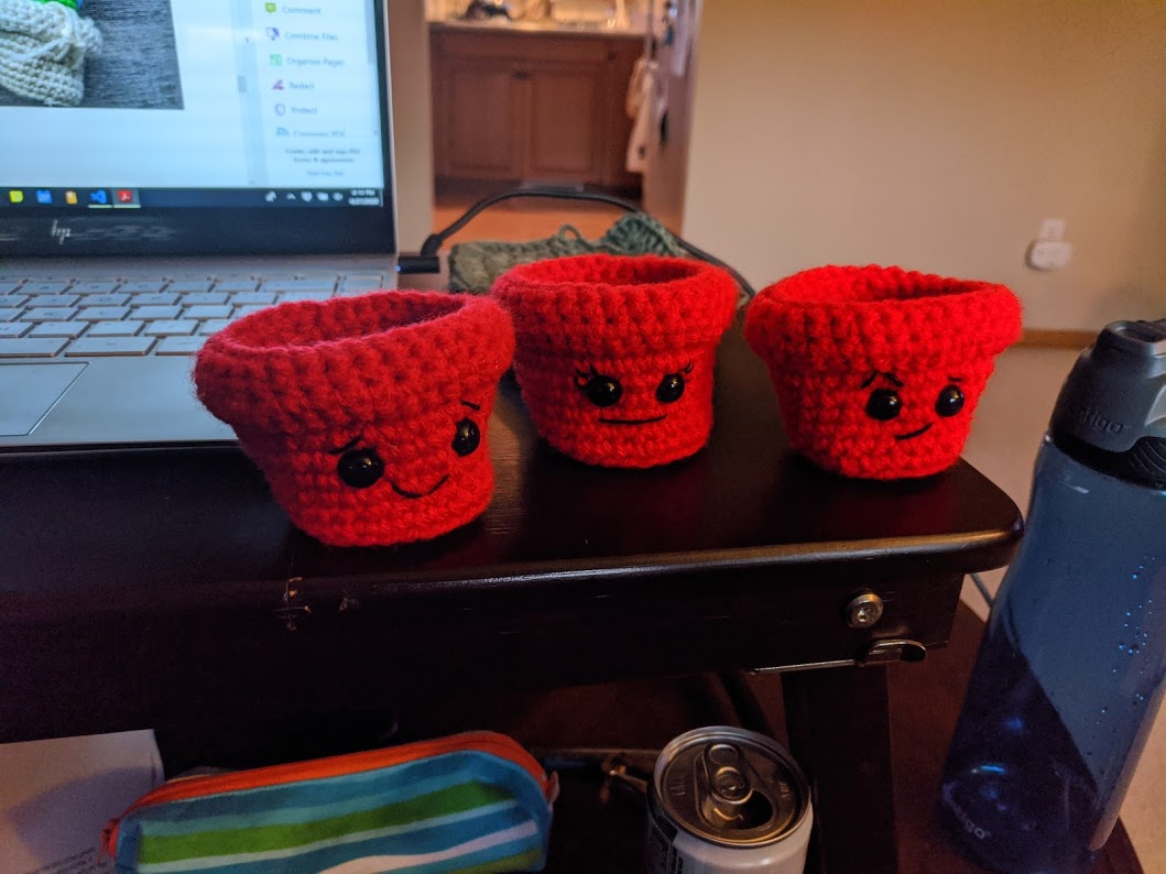 A set of 3 crocheted flower pots with faces sewn on.