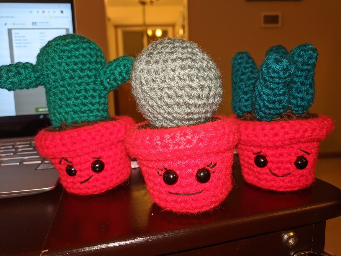 A set of 3 crocheted amigurumi, two cacti and a succulent.